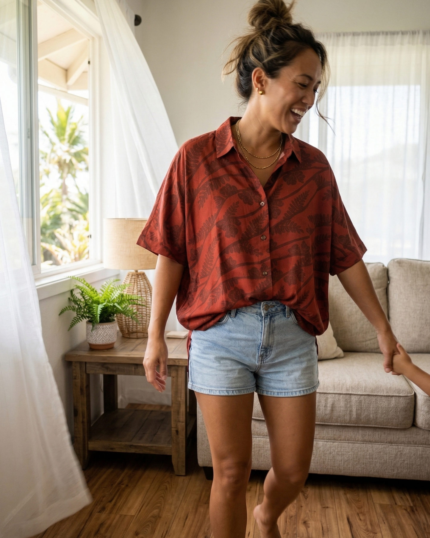 Kupukupu x Likolehua oversized button-up top in deep red with fern print, styled with denim shorts