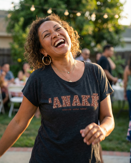 Pua Kukui ʻAnakē scoop neck tee in Vintage black, worn by woman walking through a Hawaiʻi town at golden hour.