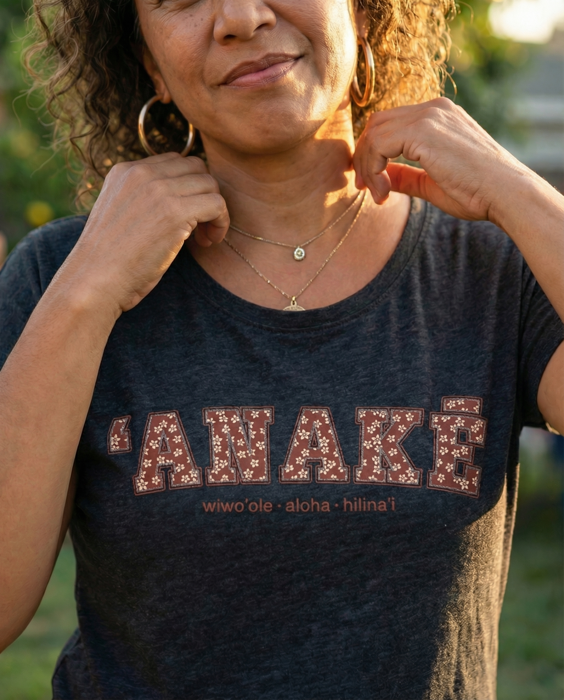 Pua Kukui ʻAnakē scoop neck tee in Vintage black, worn by woman walking through a Hawaiʻi town at golden hour.